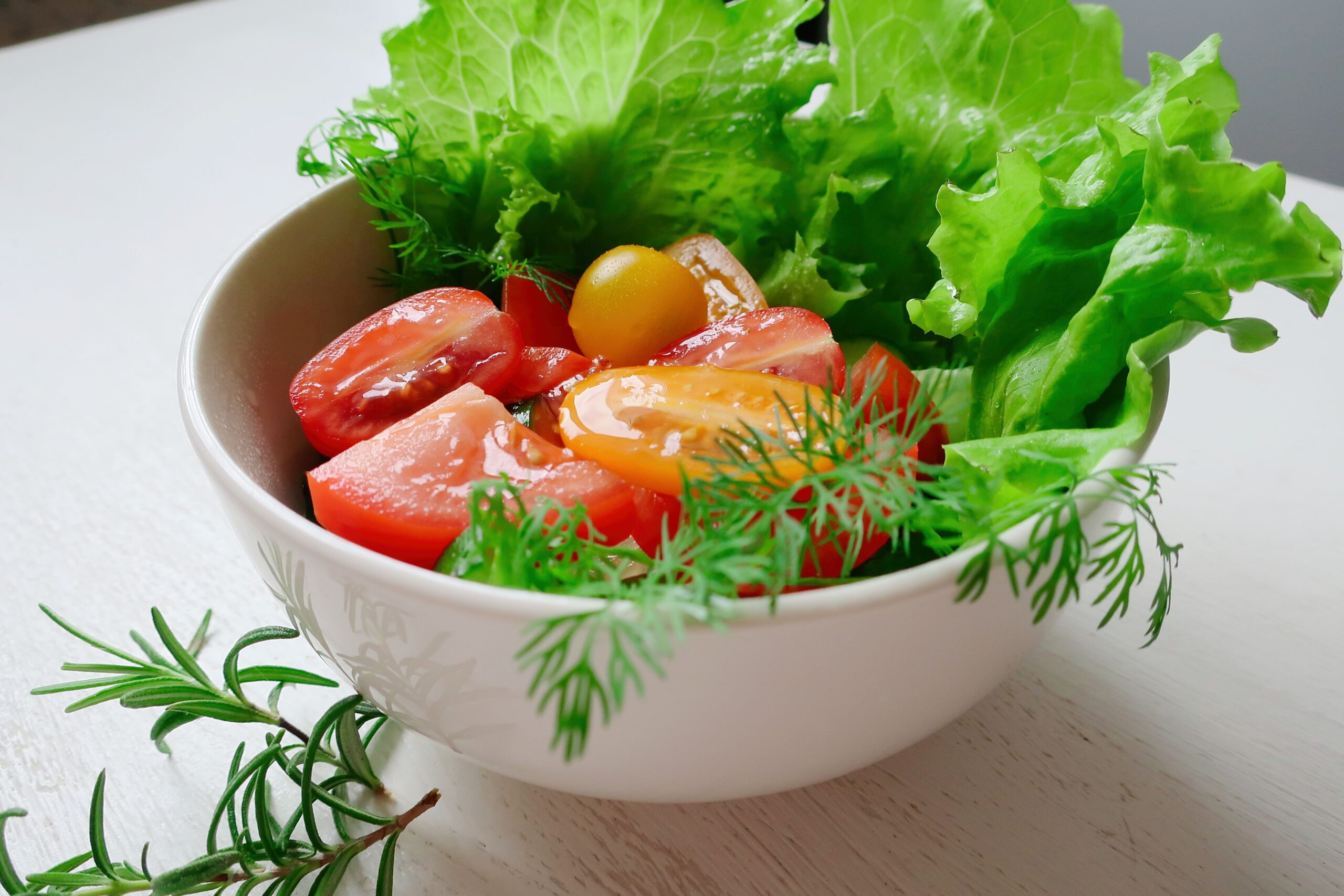 A vibrant salad composed of fresh lettuce, slices of tomatoes, and herbs, perfect for healthy eating.